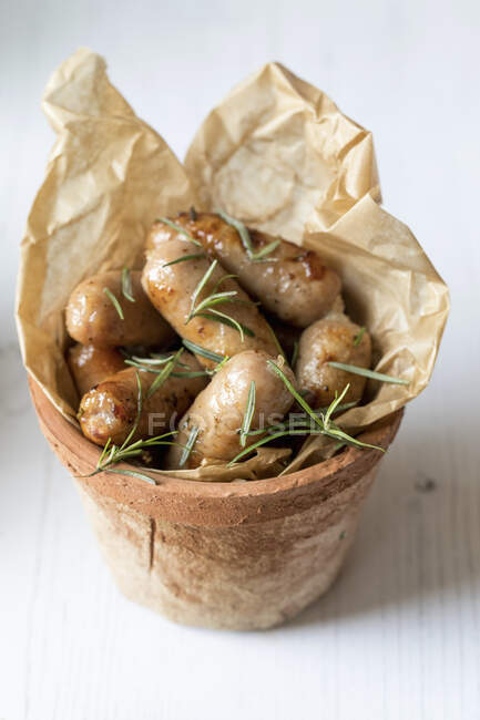 Sausages with rosemary served in a terracotta flower pot — Stock Photo