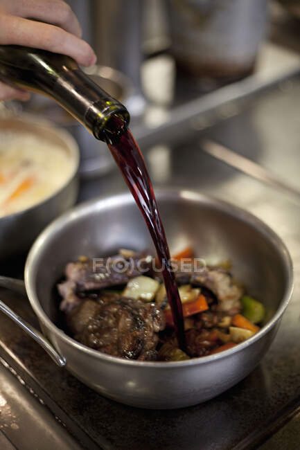 Wine being added to a pan with meat and vegetables — Stock Photo