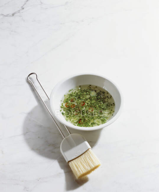 Herb grill marinade with chilli in a bowl with a brush — Stock Photo