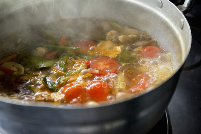Подготовка супа Том Юм с грибами, курицей, лимонной травой, чили, листьями лимона и помидорами — стоковое фото
