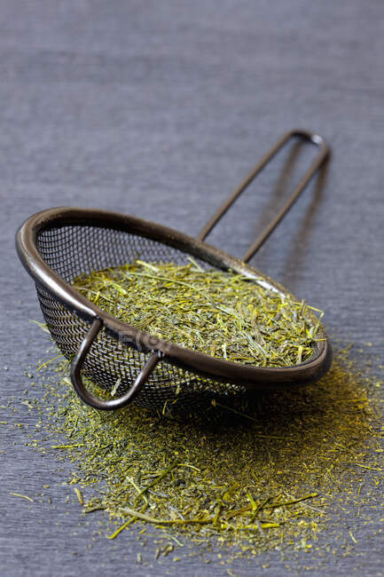 Japanese green tea leaves in a metal strainer — Stock Photo