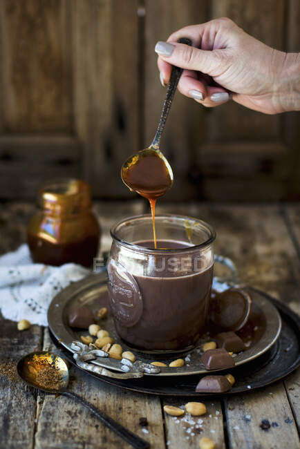 Peanut caramel being added to a cup of hot chocolate — Stock Photo