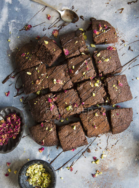 Chocolate brownies drizzeled in melted chocolate and topped with pistachio nuts and dried rose petals — Stock Photo