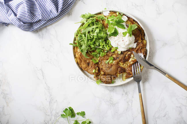 Tortilla omelette with sliced potatoes and herbs on marble table — Stock Photo