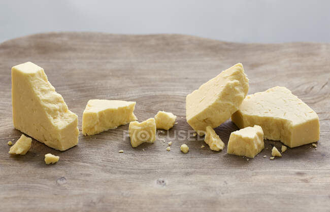 Cheddar Cheese with crumbs on rustic wooden surface — Stock Photo