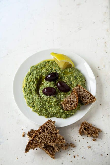 Spinach hummus with black olives and bread — Stock Photo