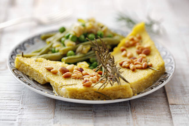 Polenta slices with pine nuts and beans — Stock Photo