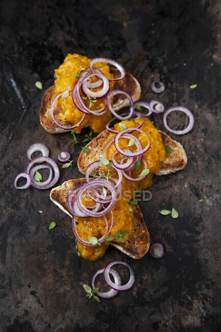 Gelber Paprikaaufstrich auf Toast mit roten Zwiebeln — Stockfoto