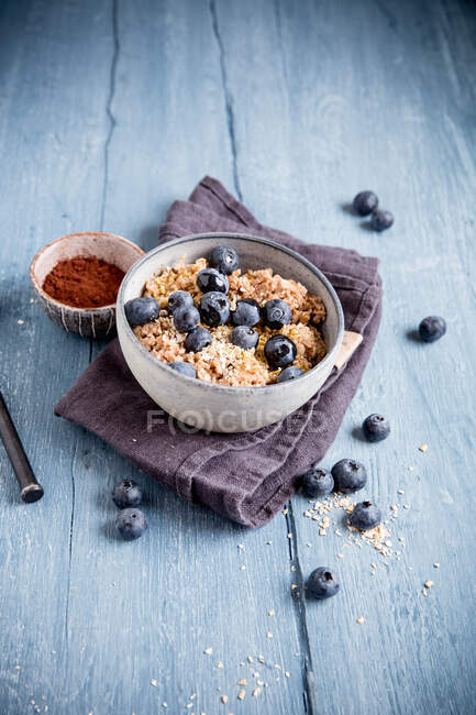 Porridge con cacao e mirtilli su superficie di legno con panno — Foto stock