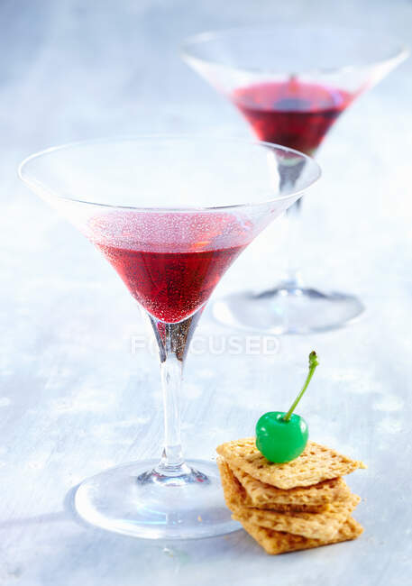 Martini Dolce con vermoth rosso, gin e granatina in bicchieri con cracker e ciliegia verde — Foto stock