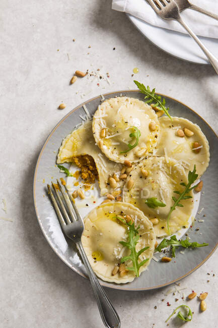 Frische hausgemachte Kürbis-Ravioli-Tortellini auf Teller mit Pinienkernen, Parmesan und Rucola — Stockfoto