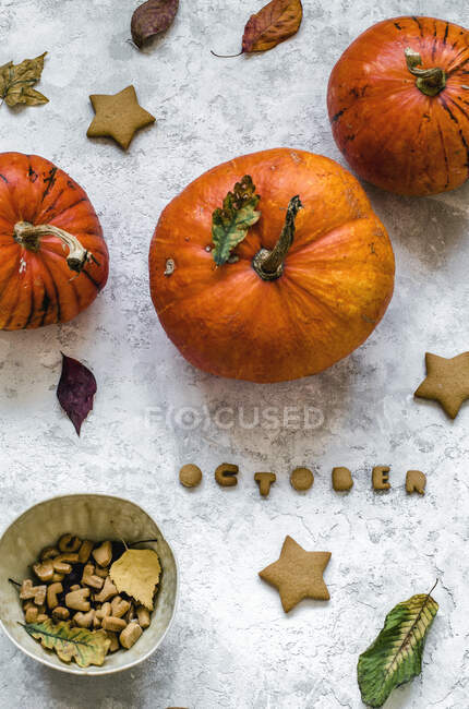 Kekse in Form von Sternen und Buchstaben, aus denen das Wort Oktober hervorgeht, Kürbisse und Herbstblätter — Stockfoto