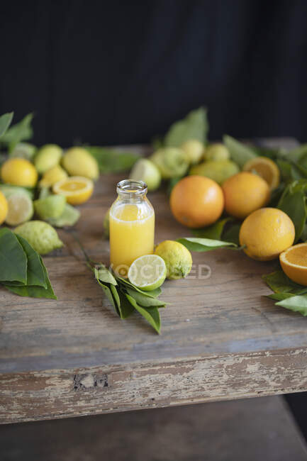 Freshly pressed orange juice and fresh citrus fruits on a rustic wooden table — Stock Photo