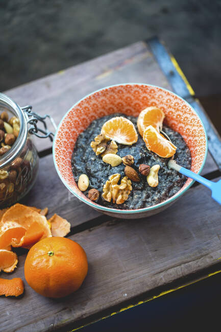 Charcoal oatmeal porridge with chia seeds, clementine and nuts — Stock Photo