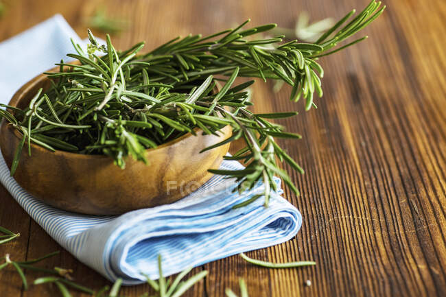 Erba di rosmarino fresco biologico su tovagliolo tessile sul tavolo di legno — Foto stock