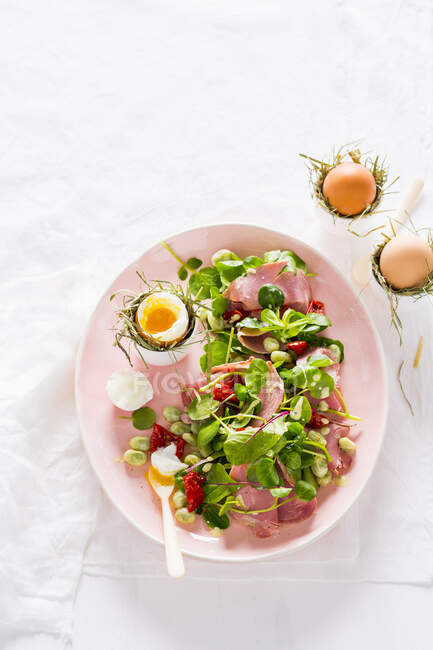 Salad with fava beans, dried tomatoes, ham and soft-boiled eggs — Stock Photo