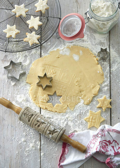 Cookie dough with cutters and a rolling pin on a floured wooden table — Fotografia de Stock