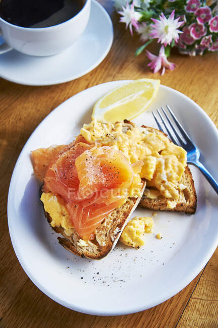 Scrambled Eggs on bread toasts with Salmon and lemon wedge — Stock Photo