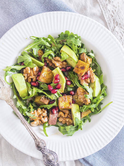Arugula salad with sweet potatoes, avocado, pomegranate and grilled nuts — Stock Photo