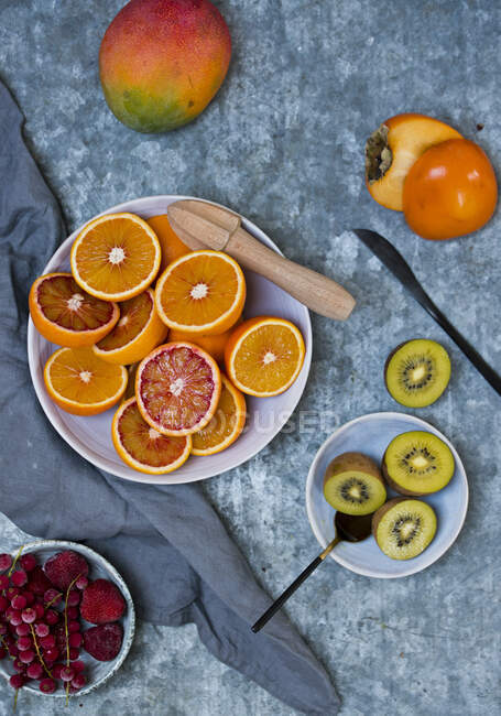 Frutas frescas: naranjas de sangre, mango, caquis, kiwis y bayas heladas - foto de stock