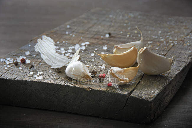 Natura morta con spicchi d'aglio, sale grosso e grani di pepe su una tavola di legno — Foto stock