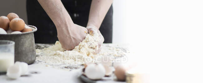 Woman preparing dough for cooking on kitchen table — Stock Photo