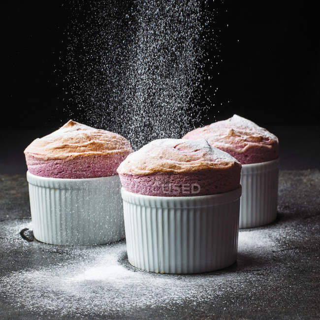 Muffin fatti in casa con zucchero a velo e cioccolato su sfondo nero. — Foto stock