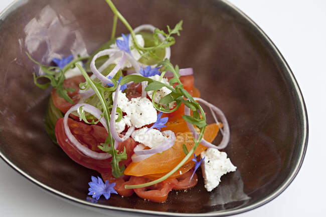 Ensalada de tomate con queso feta y flor silvestre - foto de stock