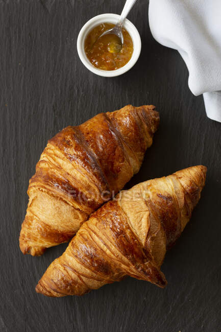 Two classic French flaky croissants with orange confiture — Stock Photo