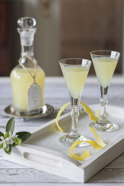 Limoncello in a carafe and two glasses on a wooden tray — Stock Photo