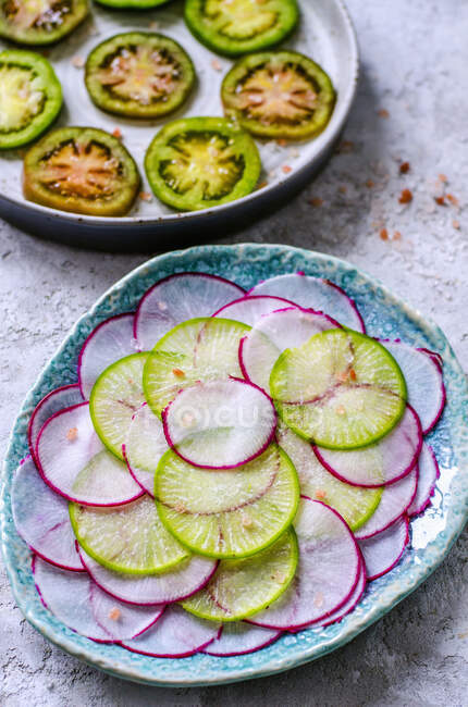 Slices of green and pink radishes and a ring of green tomatoes — Stock Photo