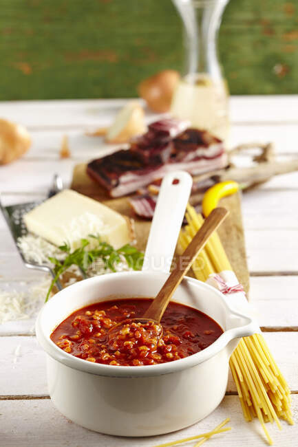 Amatriciana sauce with bacon, cheese, pasta and wine on a table — Stock Photo