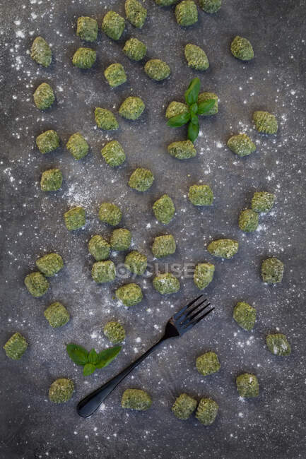 Espinacas frescas y ñoquis de albahaca sobre una superficie gris (vista desde arriba)) - foto de stock