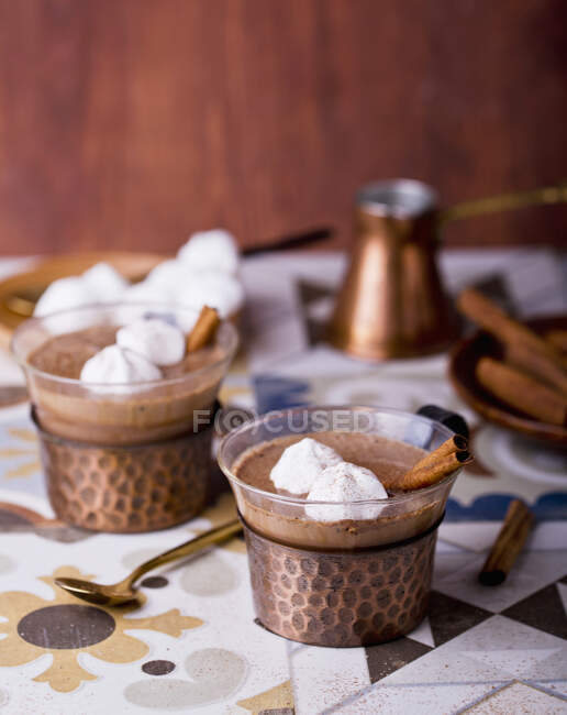 Chocolate caliente adornado con puntos merengue y palitos de canela - foto de stock