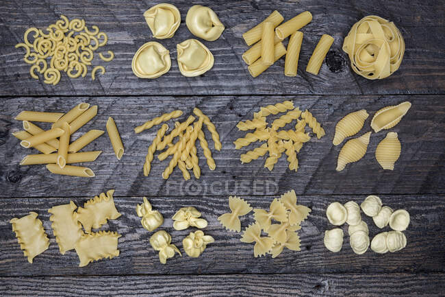 Різні види макаронних виробів на дерев'яній поверхні — стокове фото
