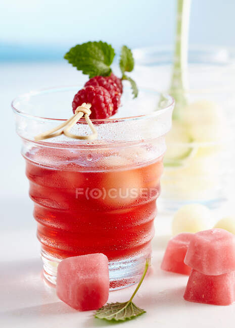 Soco com framboesas e melão de orvalho de mel servido com cubos de gelo rosa — Fotografia de Stock