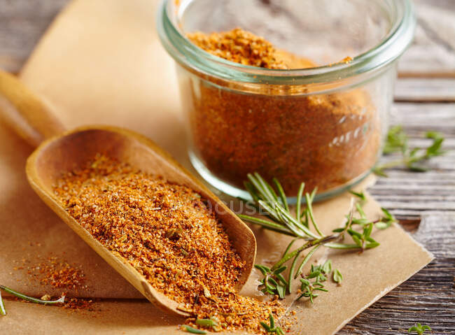 Homemade steak spice mix in a glass and on a wooden scoop — Stock Photo