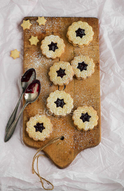 Jam sandwich biscuits on wooden board with spoons — Stock Photo