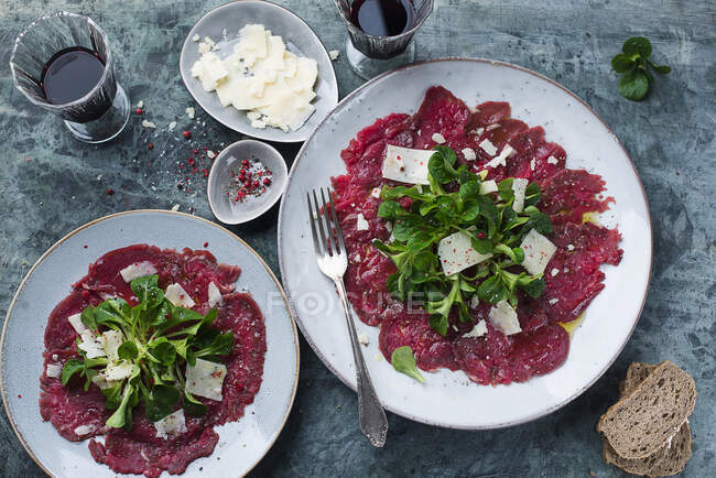 Beef carpaccio with lambs lettuce and cheese shavings — Stock Photo