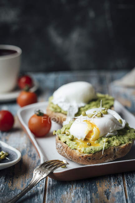 Avocado toasts with poached eggs and tomatoes — Stock Photo