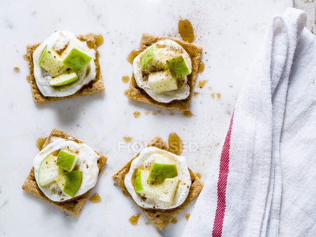 Cinnamon graham crackers toppped with yogurt and chopped green apples drizzled with honey — Stock Photo
