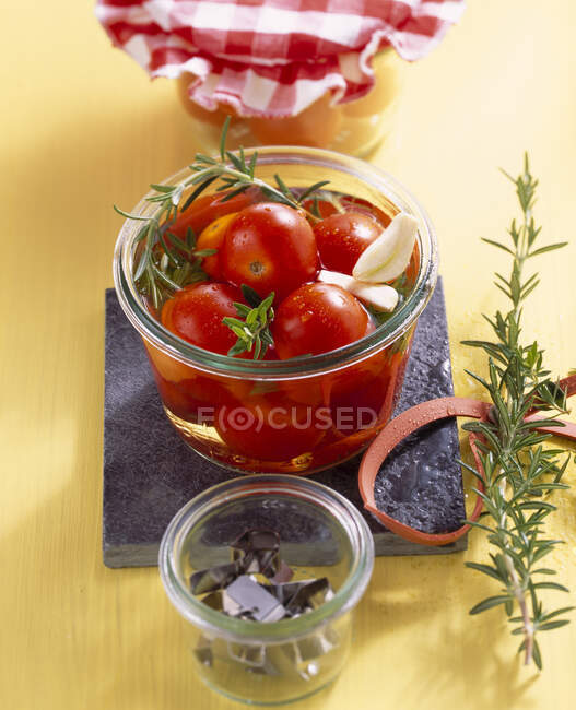 Tomates cherry en vinagre en escabeche con hierbas frescas y ajo - foto de stock