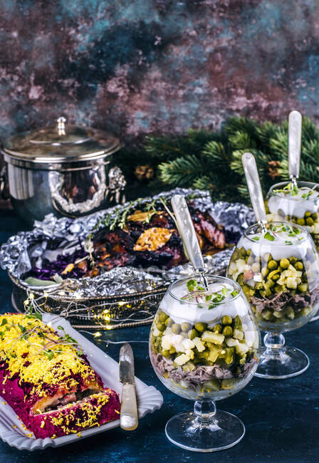 Новорічний стіл зі смаженою свининою, оселедцем у червоному буряку та овочевим салатом — стокове фото