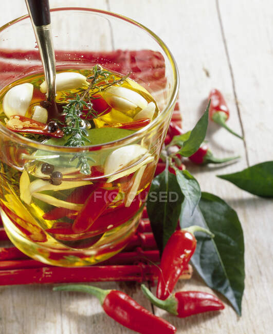 Огненное и пряное оливковое масло с чили, чесноком, тимьяном, лавром и овсянкой — стоковое фото