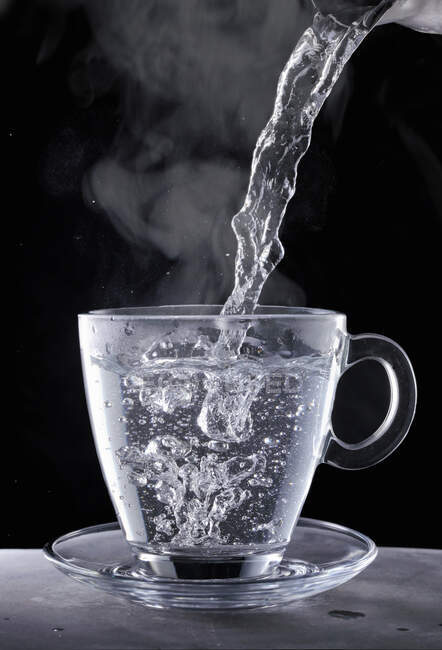 Siedendes Wasser wird in einen Glasbecher gegossen — Stockfoto
