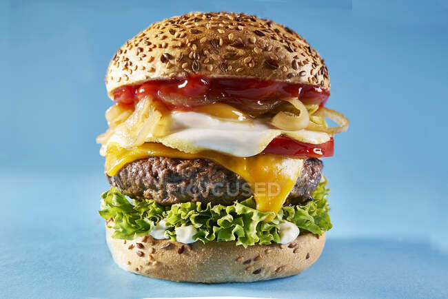 Un cheeseburger avec un oeuf frit, ketchup et oignons — Photo de stock
