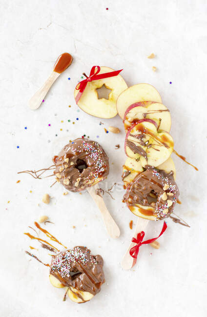 Карамельные ломтики яблока на палочках с орехами и цветными брызгами — стоковое фото