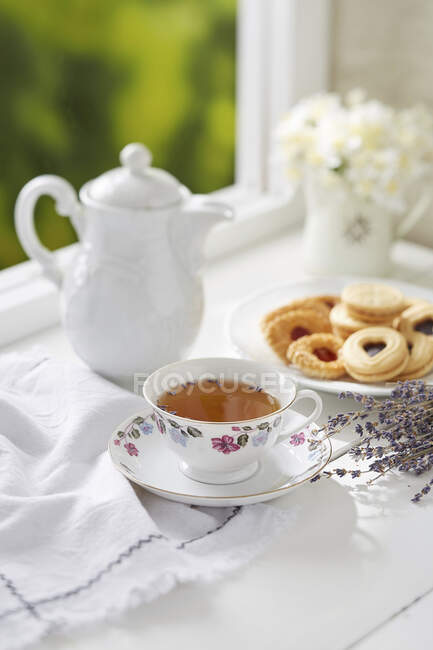 Una taza de té de lavanda con una variedad de galletas - foto de stock