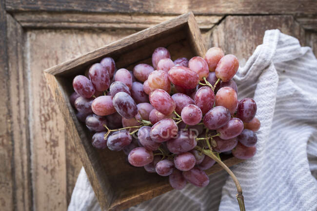 Красный виноград в деревянном ящике с тканью — стоковое фото
