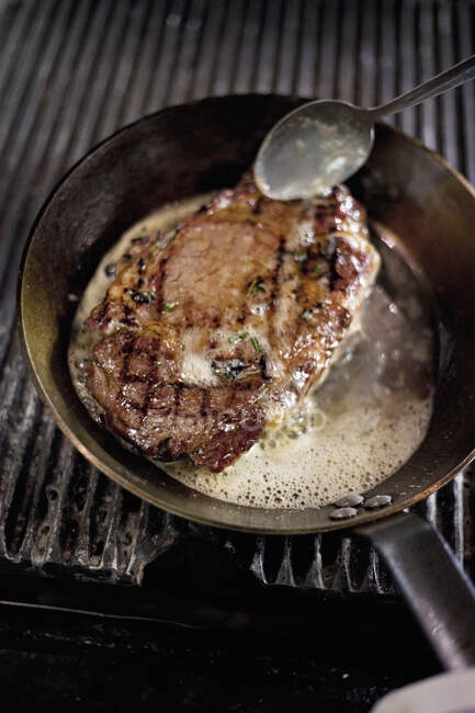 Steak arrosé de beurre dans une casserole — Photo de stock